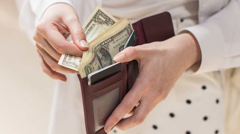 a woman takes a dollar bill out of her wallet