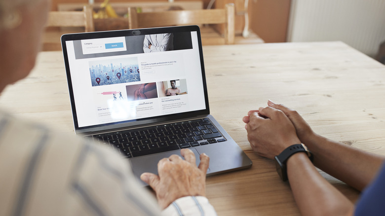 Cropped image of senior woman using a laptop.