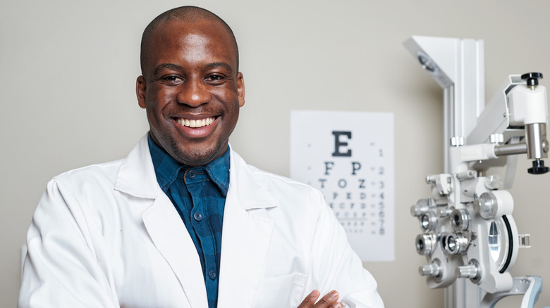 A smiling optometrist standing beside testing equipment