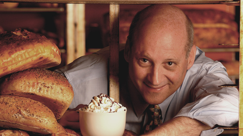 Former Panera Bread CEO Ron Shaich surrounded by fresh bread loaves and a whip-cream covered drink