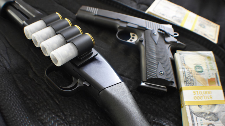 A shotgun and revolver beside stacks of money