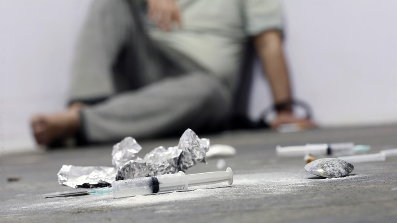 Needles on the floor in front of a sitting person
