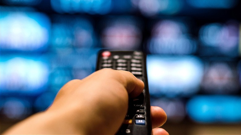 Person using remote on TV