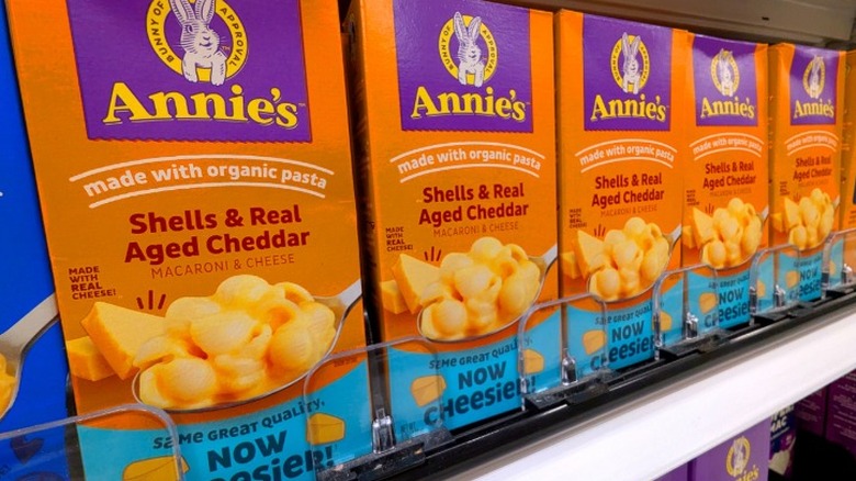 Boxes of Annie's organic macaroni and cheese lined up on a store shelf.