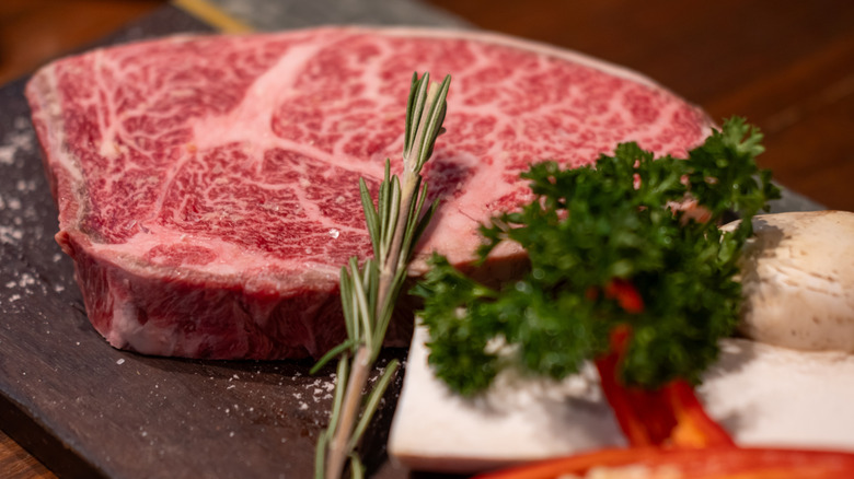 Wagyu beef on a cutting board with vegetables