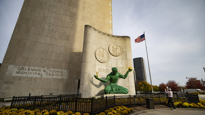 A man taking a picture of The Spirit of Detroit sculpture.