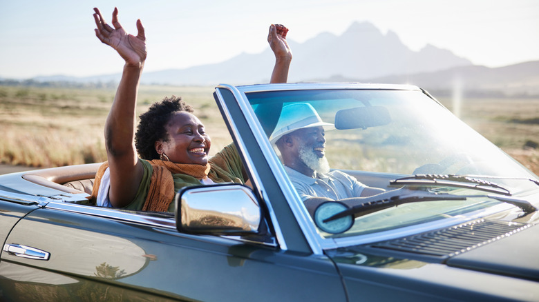 Senior couple driving a convertible car.