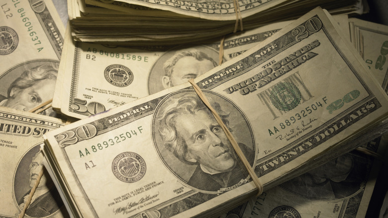 A stack of $20 bills rubber banded together with other stacks of bills under it.