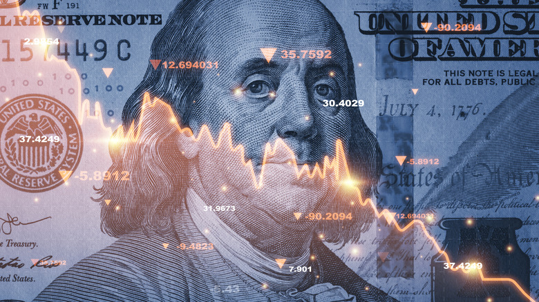 A close-up of a dollar bill with a downward trending graph overlayed on top of it