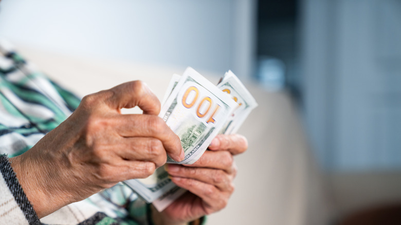 Faceless senior counting $100 bills