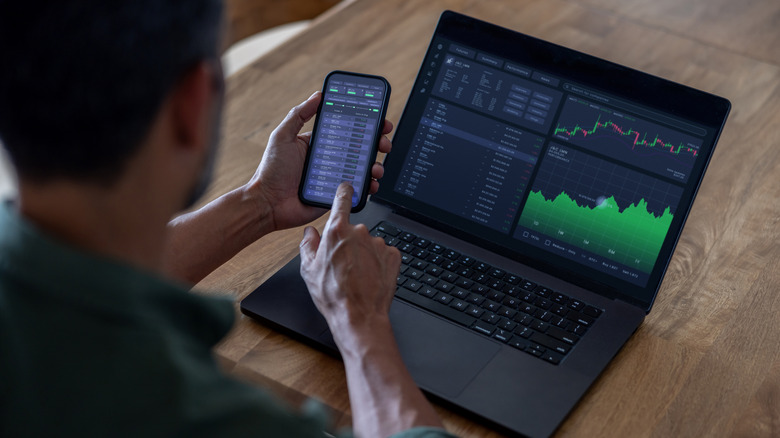 crypto trader looking at price data on their phone and laptop