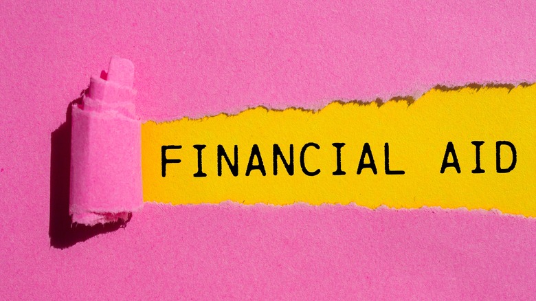 Financial aid message written on ripped torn pink paper with yellow background.