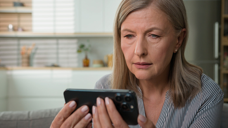 A female grandmother looking anxiously at her mobile phone