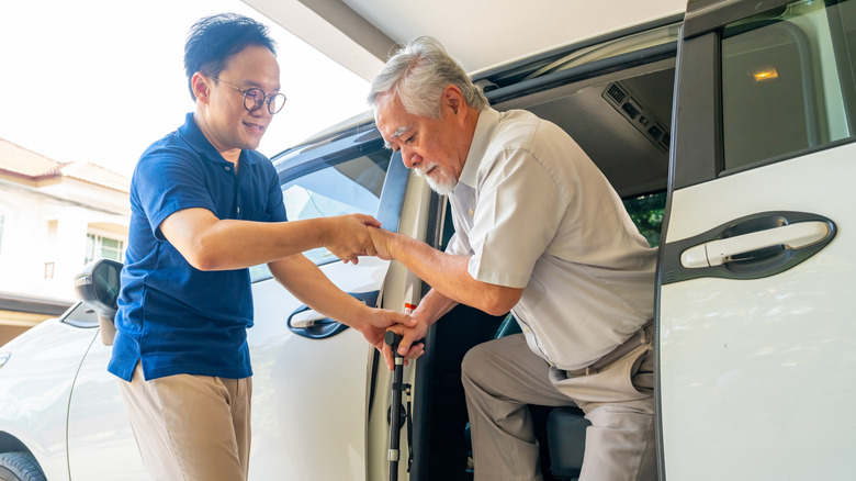Old man getting helped out of a car