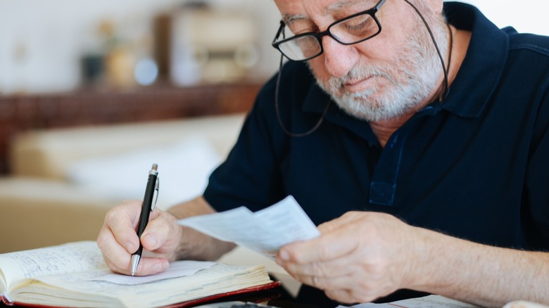 Senior man with glasses calculating finances and writing with a pen and paper