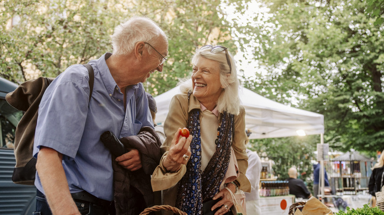 Two older people sampling food at an outdoor market