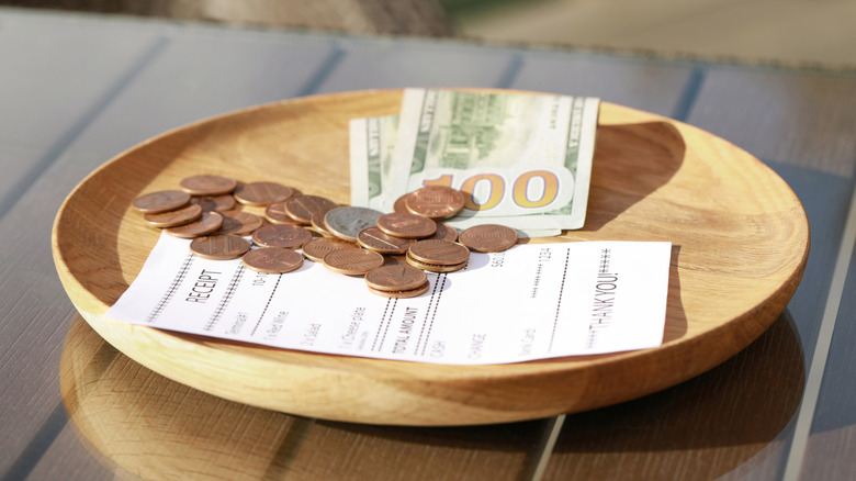 Wooden plate with payment for order and receipt on table