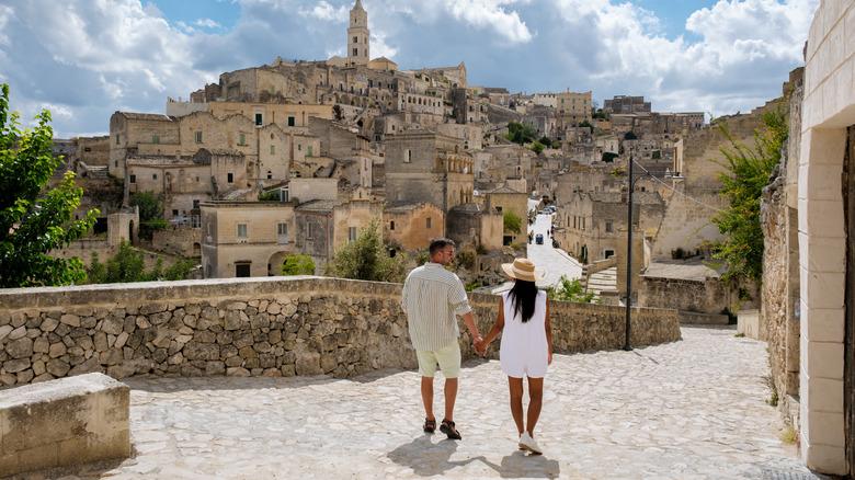 Man and woman tourists strolling on cobblestones in Matera