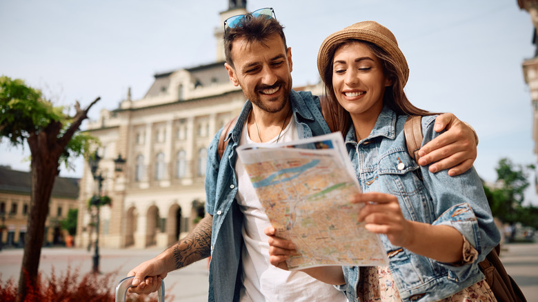 Happy couple enjoying in travel while exploring a map during their walk through the town.