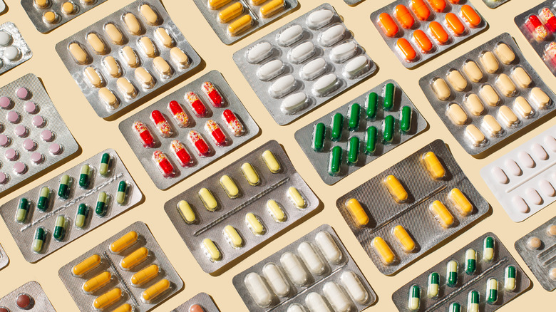 Colorful blister packs full of pills against a cream-colored background.