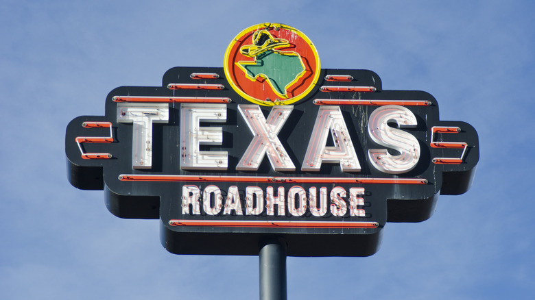 A Texas Roadhouse sign, high in a blue skiy.