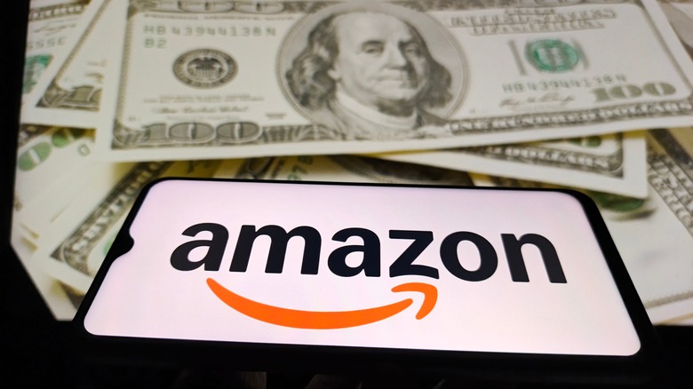 Amazon logo on a smart phone and hundred dollar bills