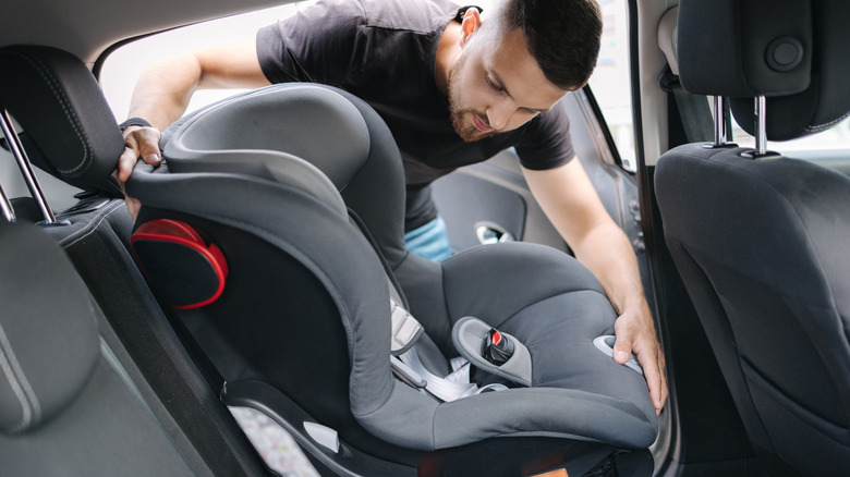 Man putting a car seat in his vehicle