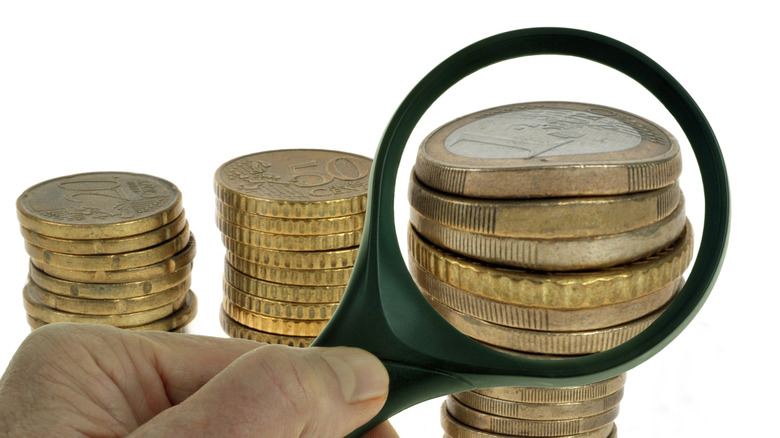 Stacks of Euros and european currency under a magnifier.