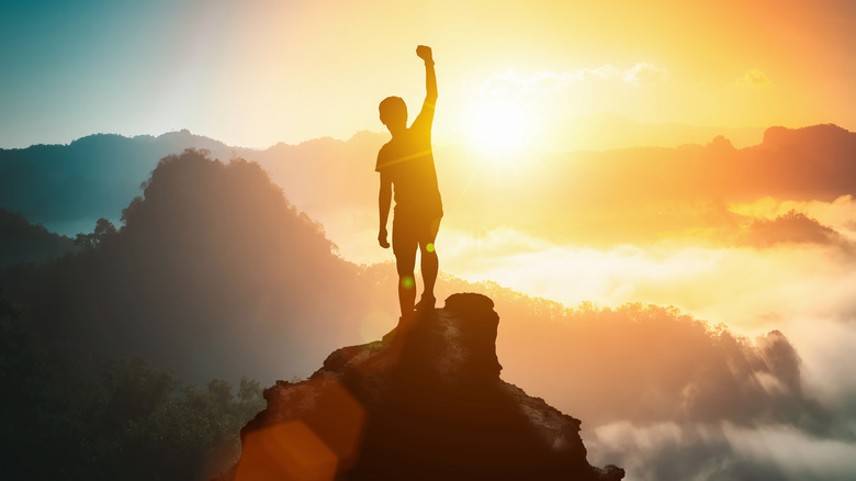 man standing on mountain, fist raised