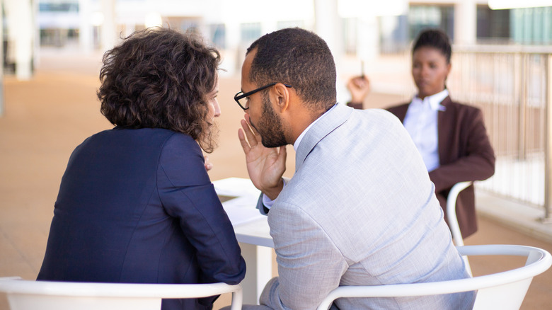 Man whispering into a woman's ear
