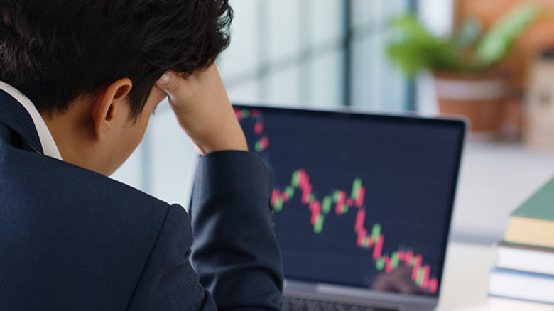 Upset man looking at a computer screen showing a chart with a downward trend