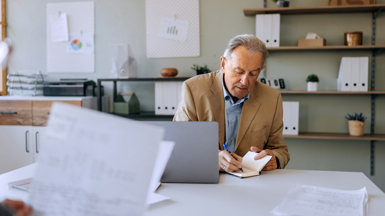 Senior man working and writing in notebook