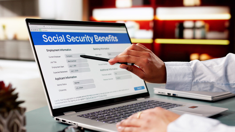 Someone points at a laptop screen with a Social Security Benefits application