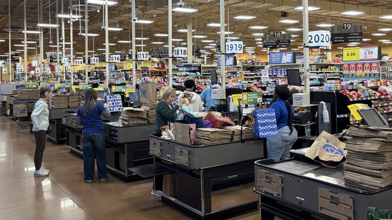 Kroger customers checking out while employees scan products and bag groceries