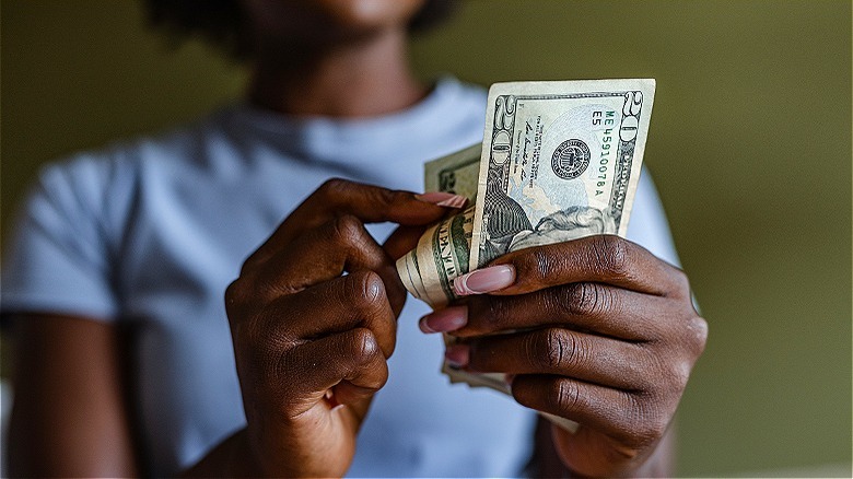 Person counting $20 bills cash