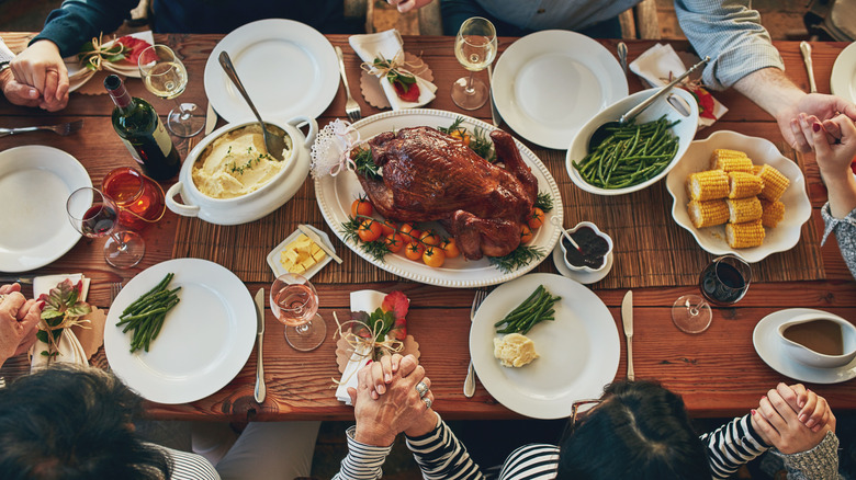 people holding hands around dinner table