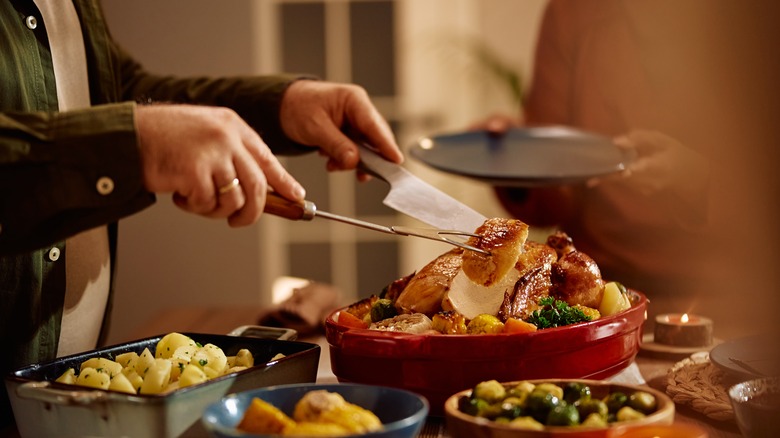 person serving a slice of turkey from red dish