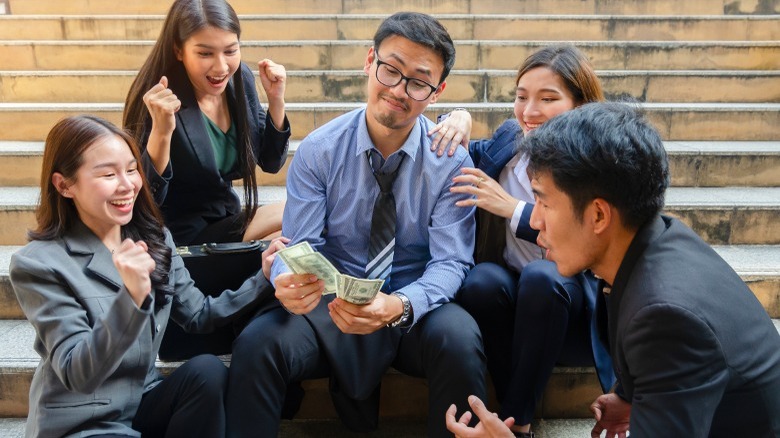 Person counting money with friends