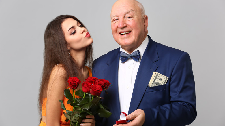 Older bald man proposing to young woman