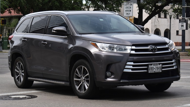 A grey Toyota Highlander SUV cruising near a beautiful nature reserve.