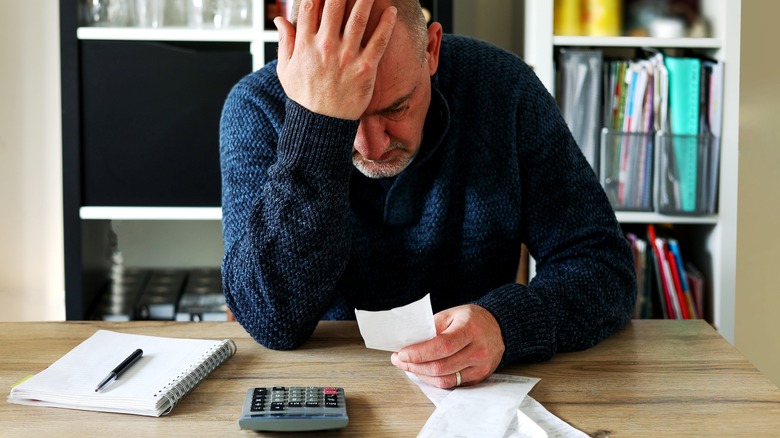 Sad man staring at receipts