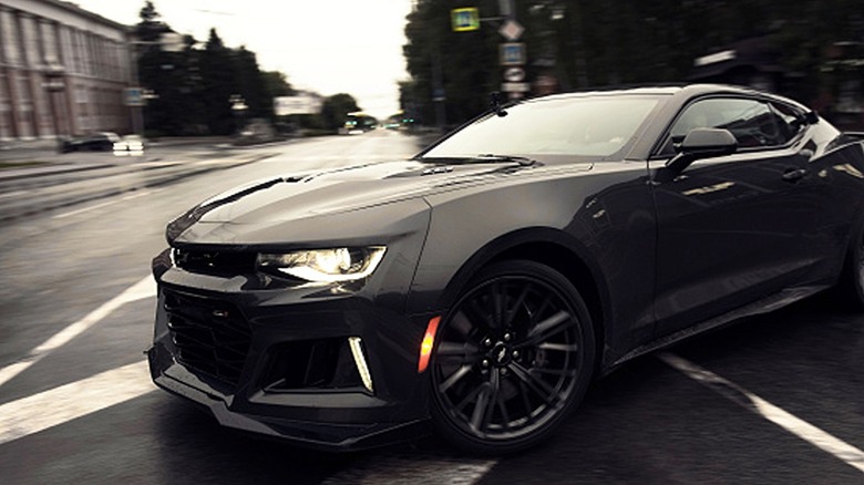 A Black Chevrolet Camaro ZL1 speeding around a city corner in the rain.
