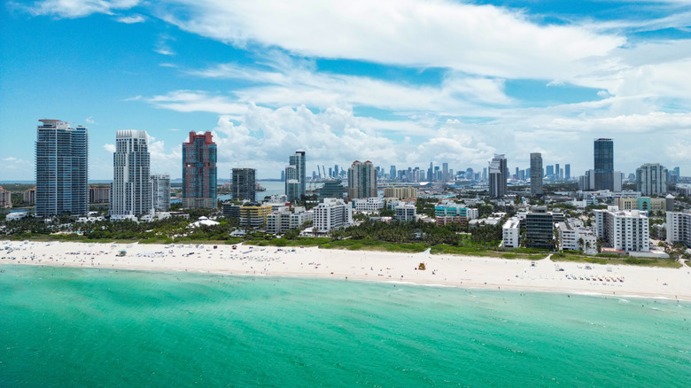 A vast Miami beach in front of a large concentration of office buildings, apartments, and hotels