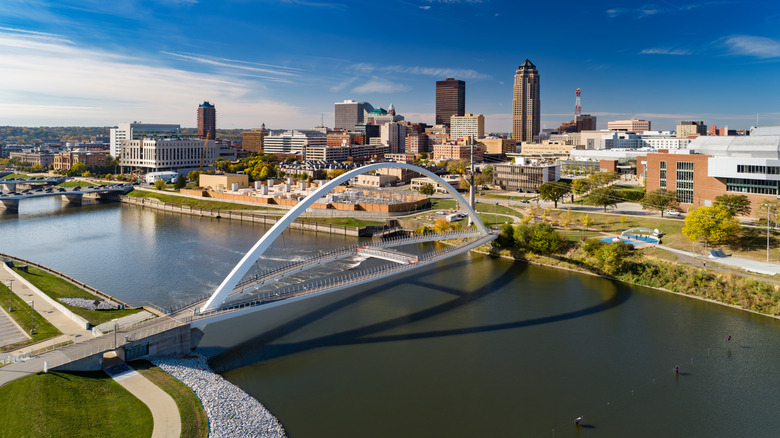 Aerial of the Des Moines Riverwalk bridge and the Des Moines River, with the Downtown Des Moines skyline in the background.