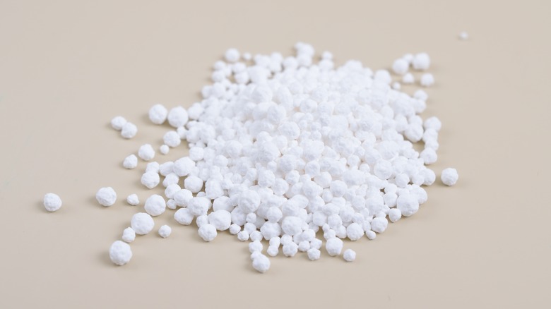 A pile of Calcium Chloride on a tan background.