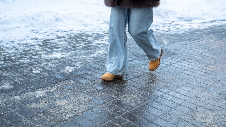 Woman walking on the street treated with rock salt.