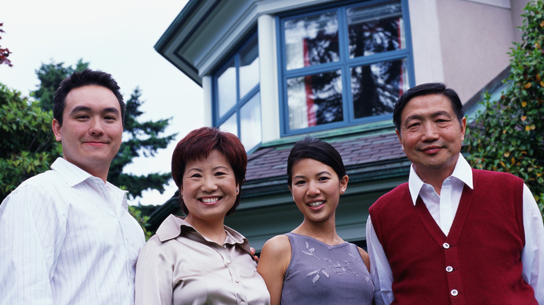 A family standing under a windowsil smiling for a family photo.