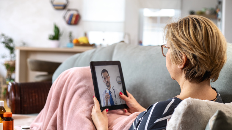 Mature woman using digital tablet for conversation with her doctor.