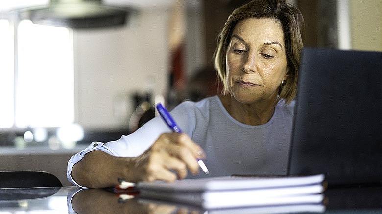 Person making notes at laptop