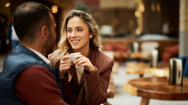 A joyful conversation between two friends enjoying coffee in a cafe setting.